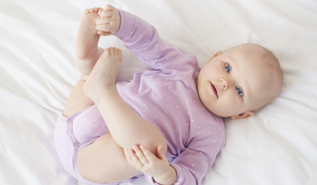 Милый голубоглазый малыш на белом покрывале