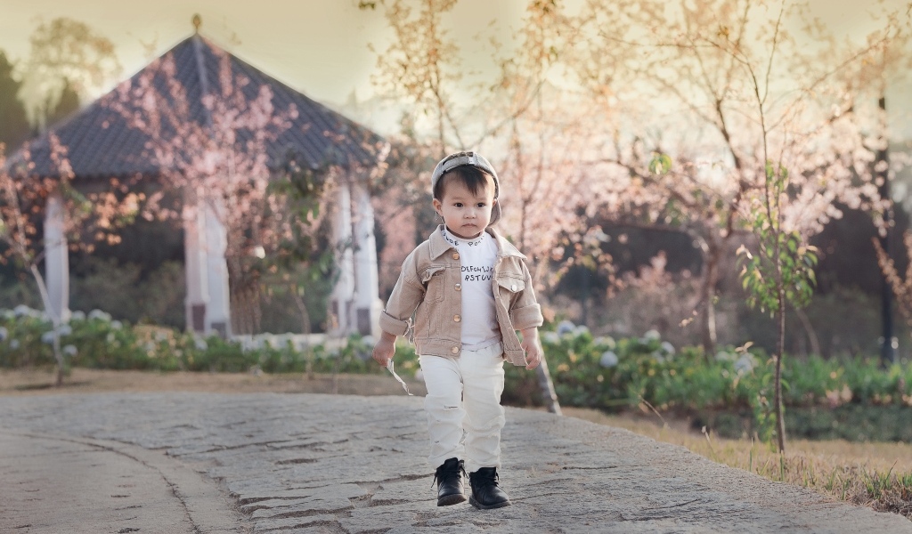 Милый мальчик гуляет по дороге у дома