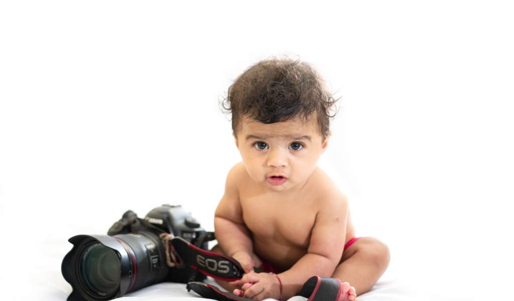 Милый ребенок с фотоаппаратом на белом фоне