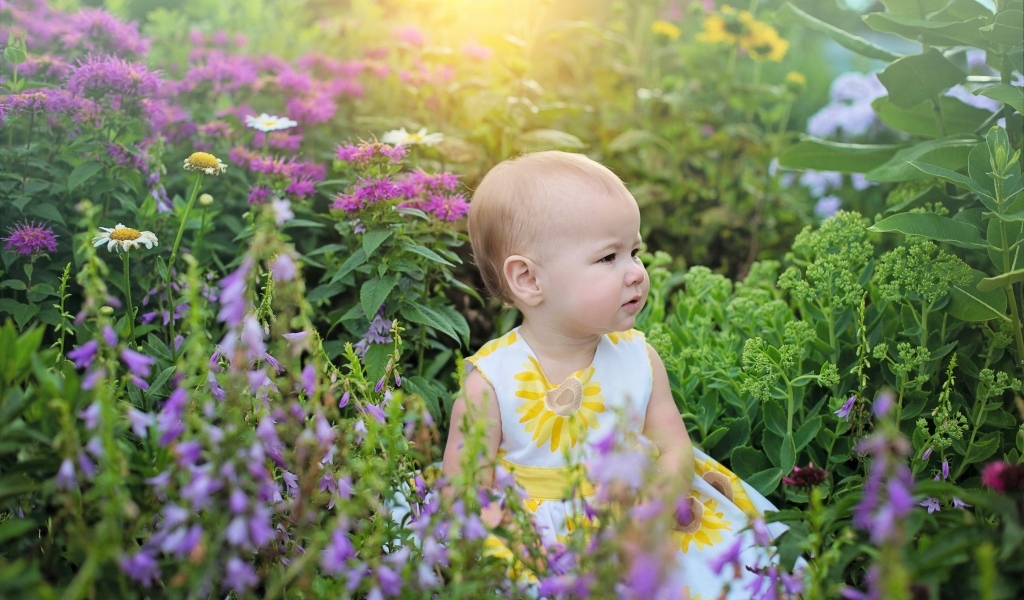 Милая девочка в платье сидит в цветах