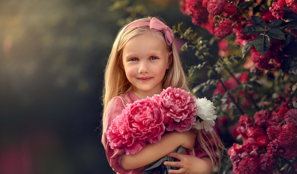 Милая маленькая девочка с букетом пионов