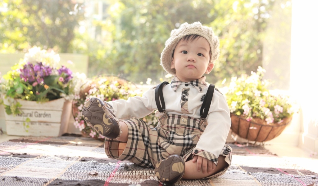 Смешной мальчик азиат у цветов