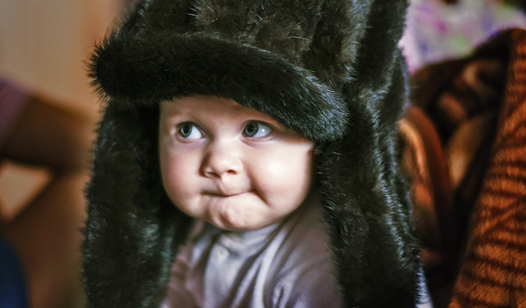 Смешной ребенок в черной меховой шапке