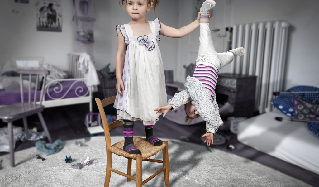 Девочка держит маленького брата за ногу