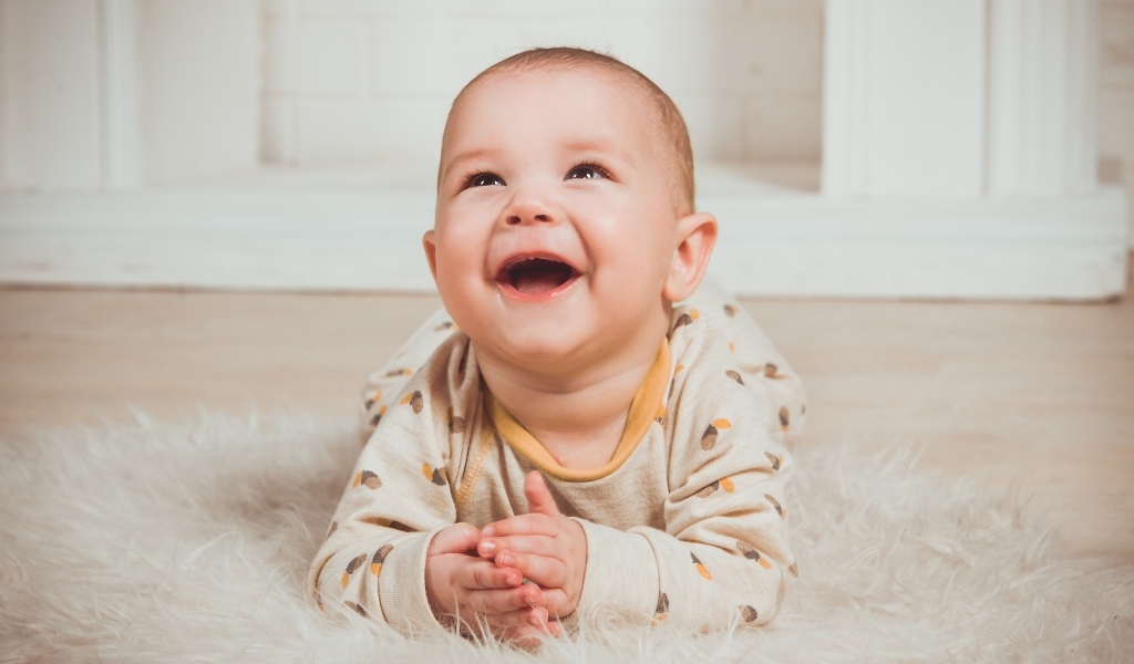 Смеющийся малыш лежит на полу