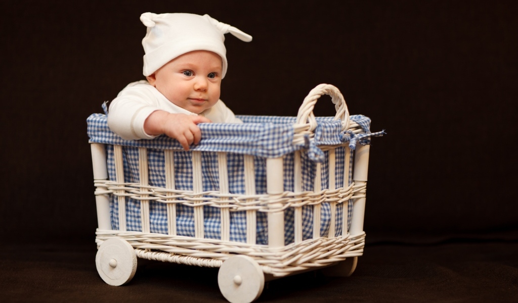 Маленький ребенок в колыбели на коричневом фоне