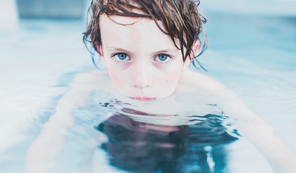 Маленький голубоглазый мальчик в бассейне