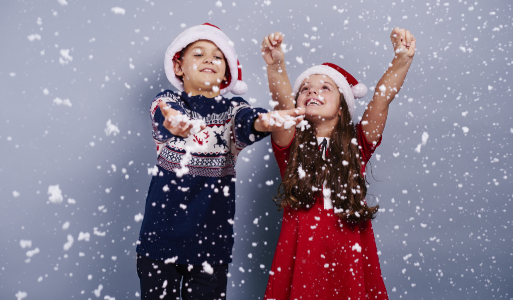 Маленькие мальчик и девочка ловят снег