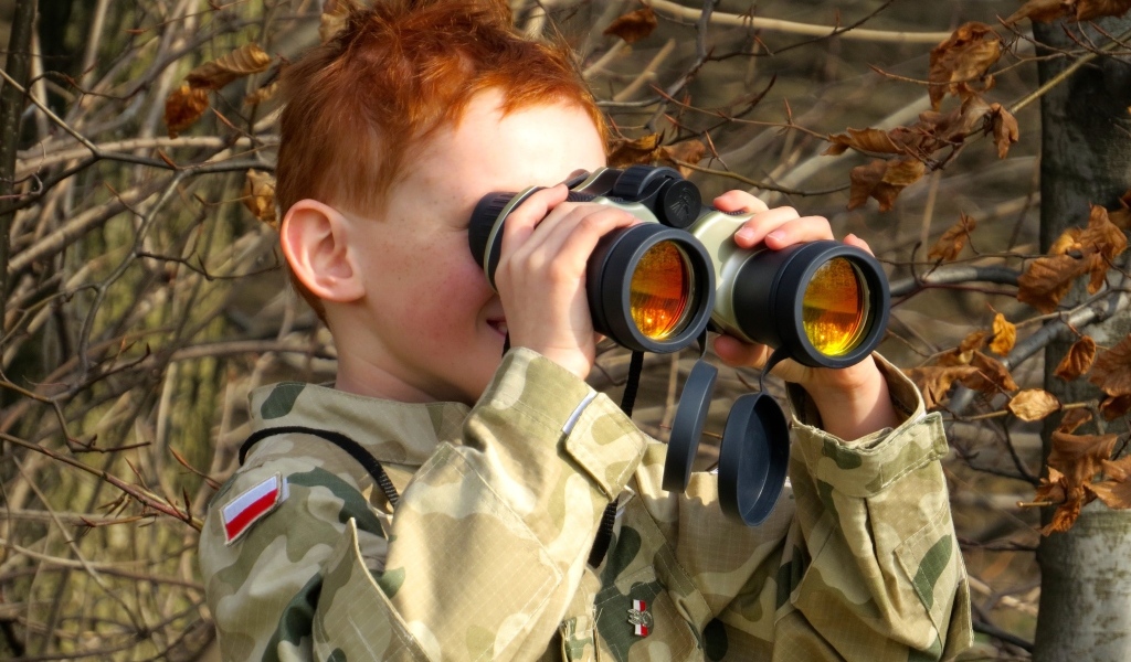 Маленький мальчик в военной форме с биноклем в руках