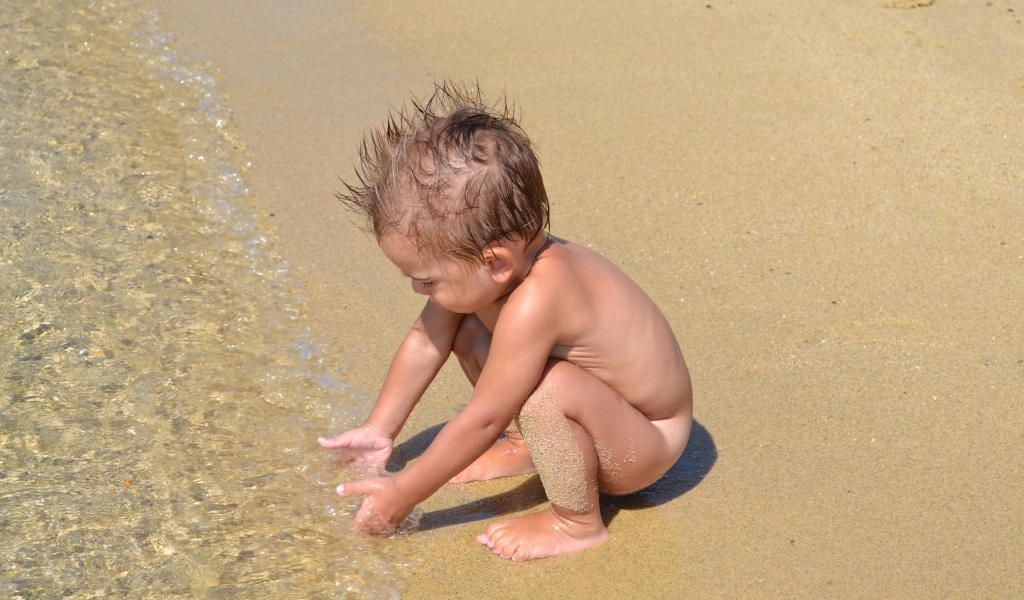 Маленький мальчик на пляже у моря на песке