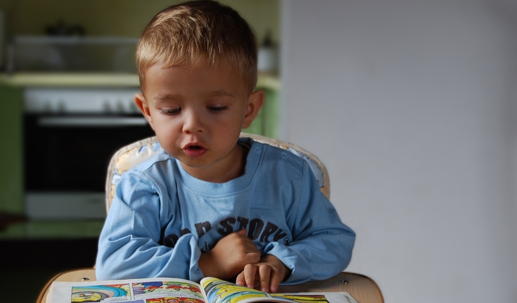 Маленький мальчик читает интересную книгу