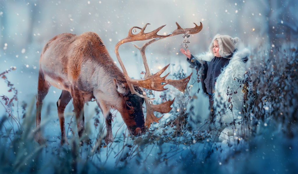 Маленький мальчик с оленем на природе зимой