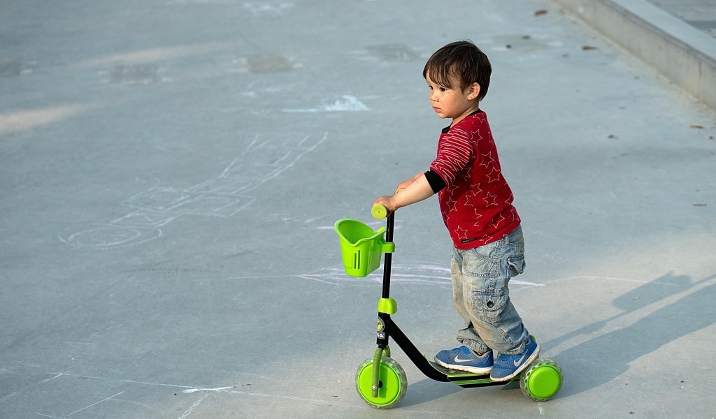 Маленький мальчик с зеленым самокатом