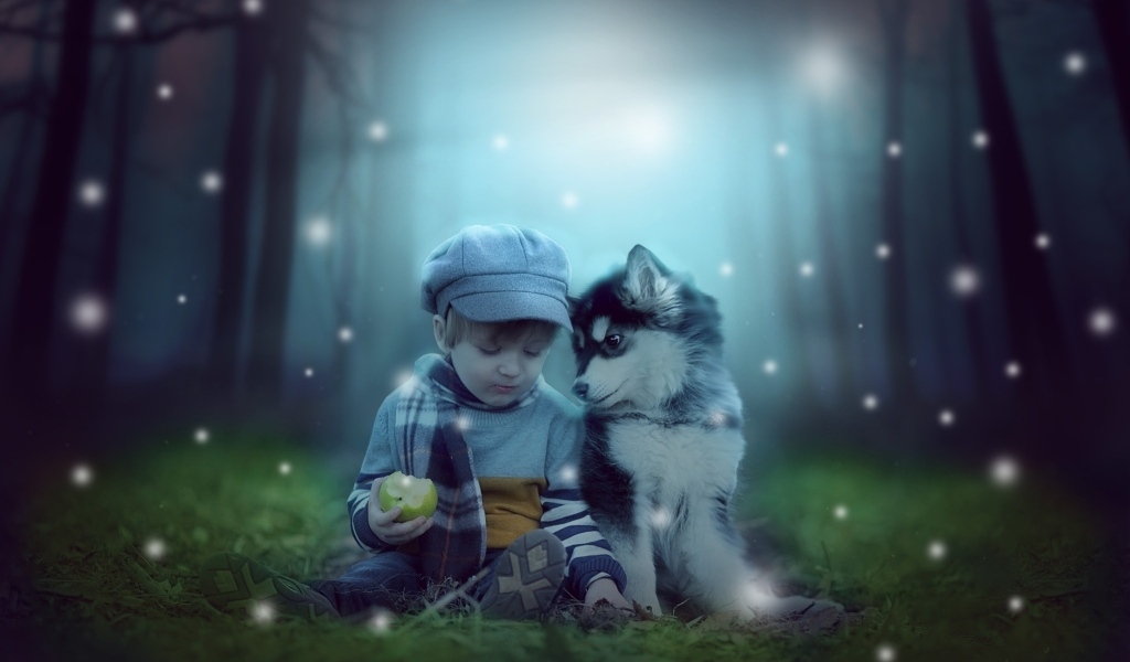 Маленький мальчик с щенком сидят на траве в лесу