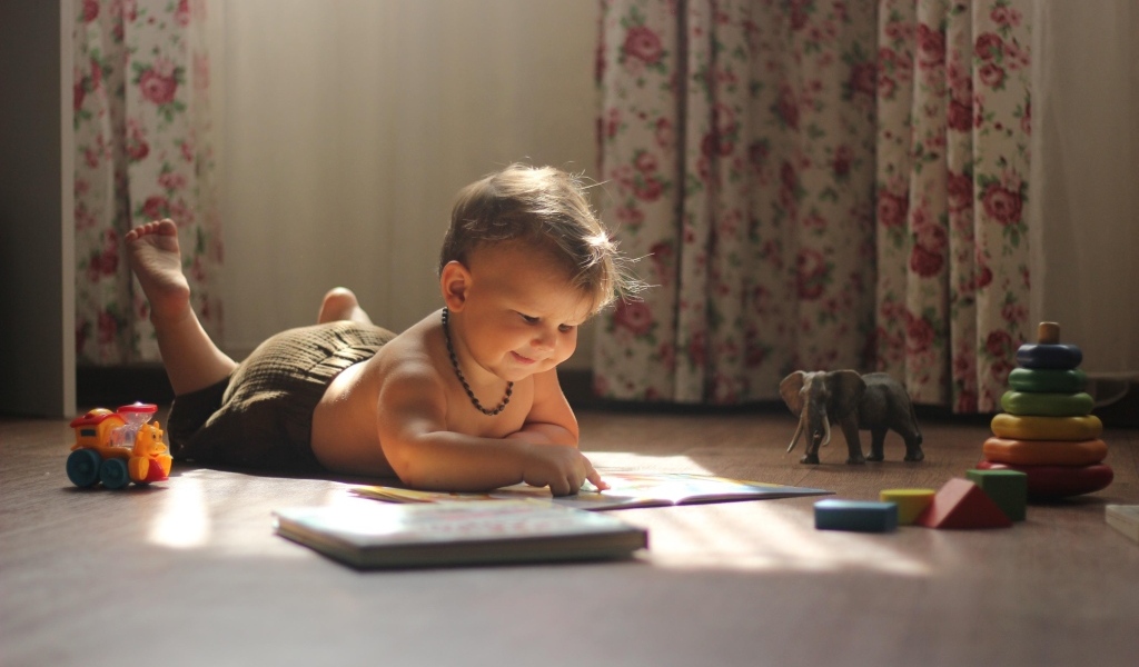 Маленький мальчик с игрушками читает книгу