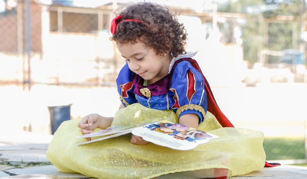 Маленькая девочка в костюме Белоснежки с книгой