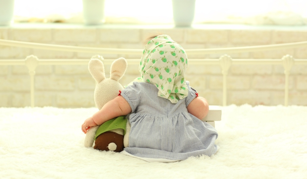 Маленькая девочка обнимает игрушечного зайца