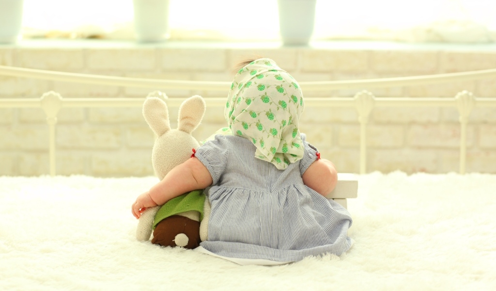 Маленькая девочка сидит с игрушкой