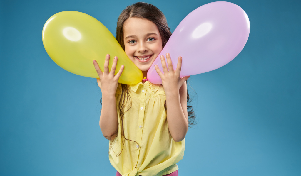 Маленькая девочка с воздушными шариками на голубом фоне