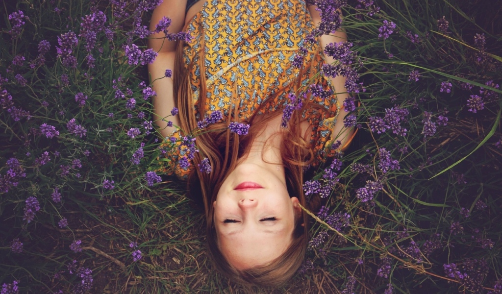 Маленькая девочка с закрытыми глазами лежит в цветах