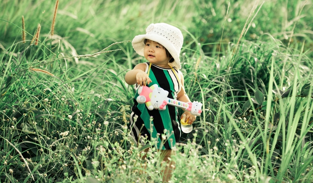 Маленькая девочка с игрушечной гитарой в траве