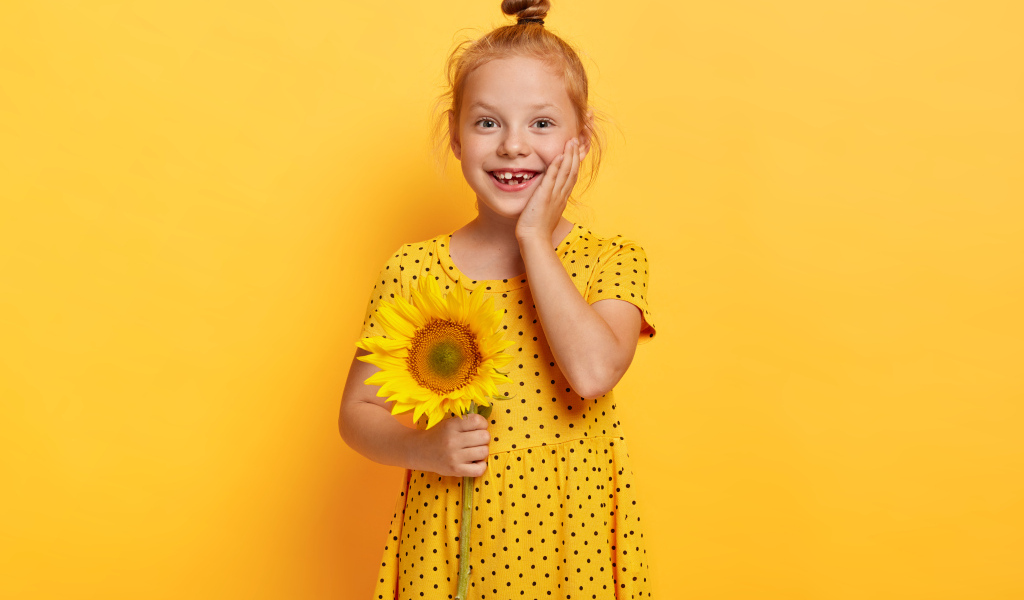 Маленькая рыжеволосая девочка с подсолнухом в руках