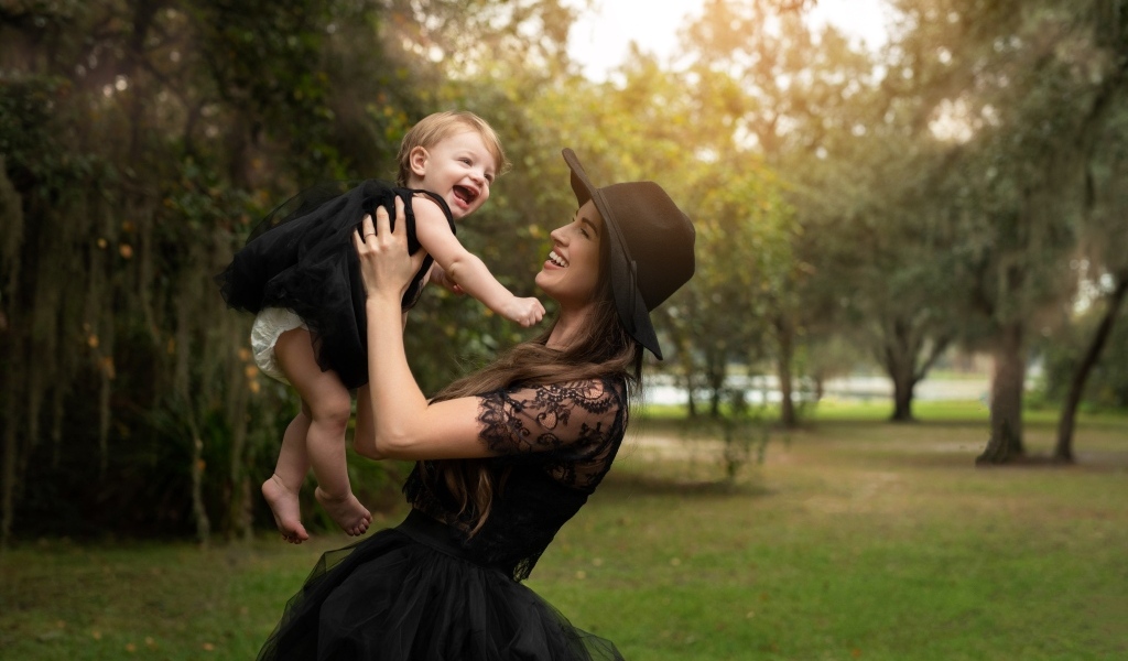 Мама держит улыбающуюся дочь на руках