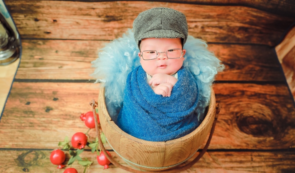 Новорожденный малыш в покрывале с кепкой на голове