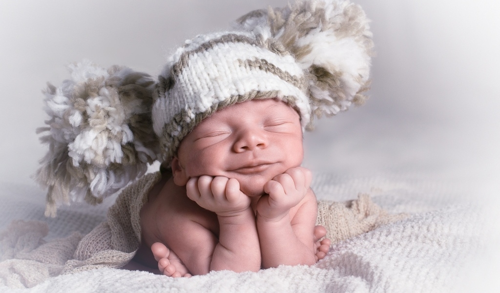 Новорожденный младенец в большой вязаной шапке