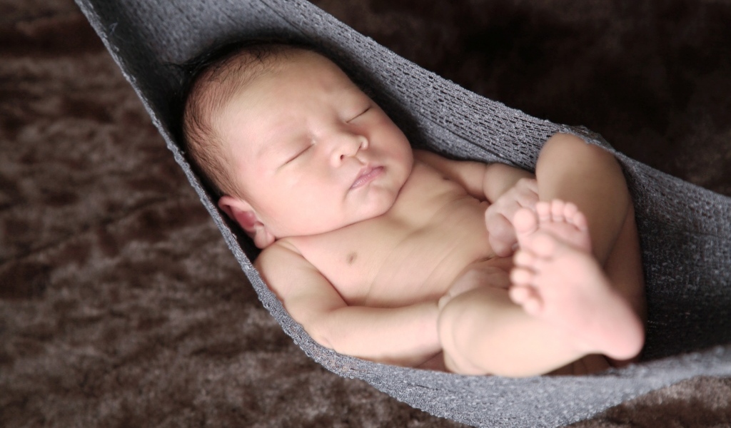 Новорожденный спящий малыш в вязаном гамаке