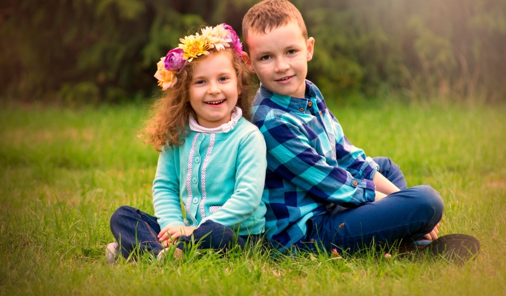 Рыжеволосые мальчик и девочка сидят на траве