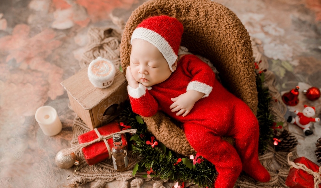 Спящий новорожденный ребенок в красном новогоднем костюме