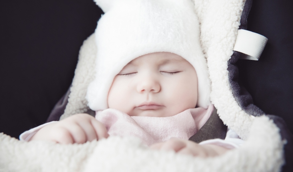 Спящий новорожденный ребенок в белой шапке