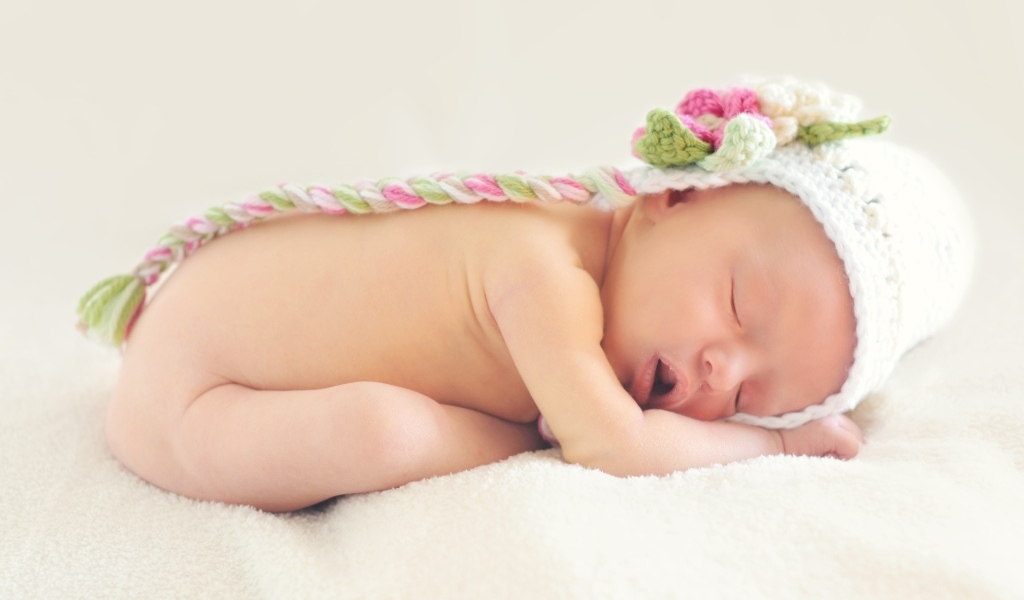 Спящая новорожденная девочка с вязаной шапке