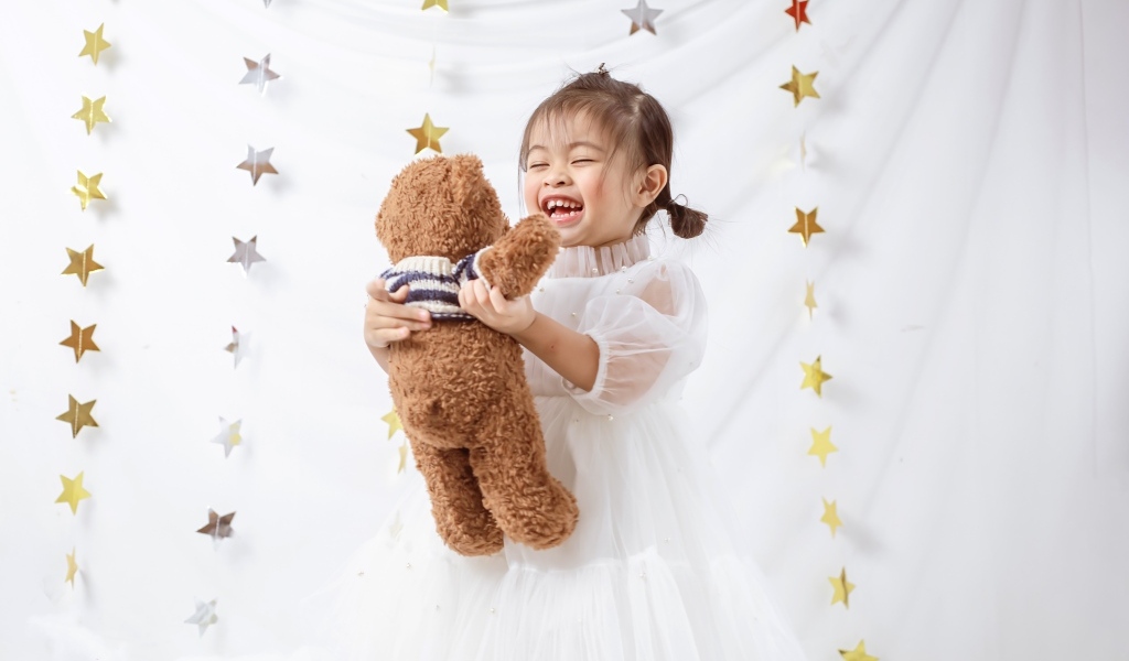 Улыбающаяся девочка азиатка с игрушечным медведем