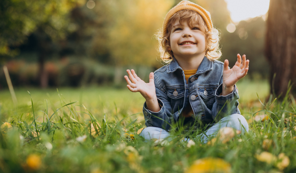Улыбающийся ребенок сидит на траве