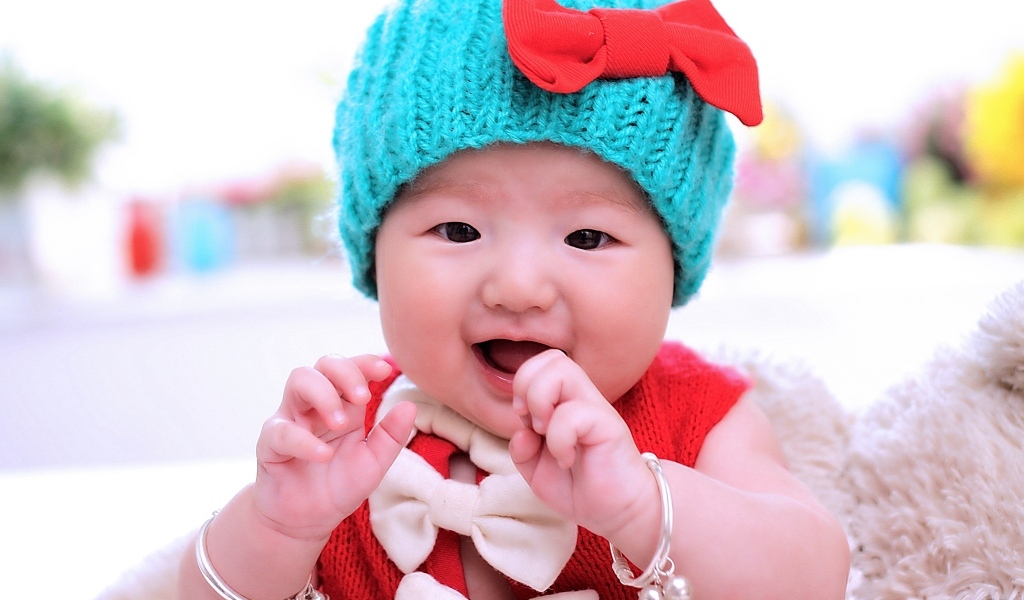 Улыбающаяся девочка в зеленой вязаной шапке