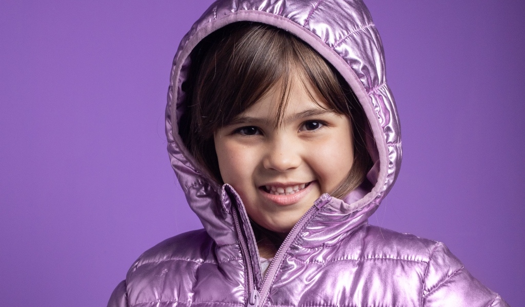 Улыбающаяся девочка в сиреневой куртке