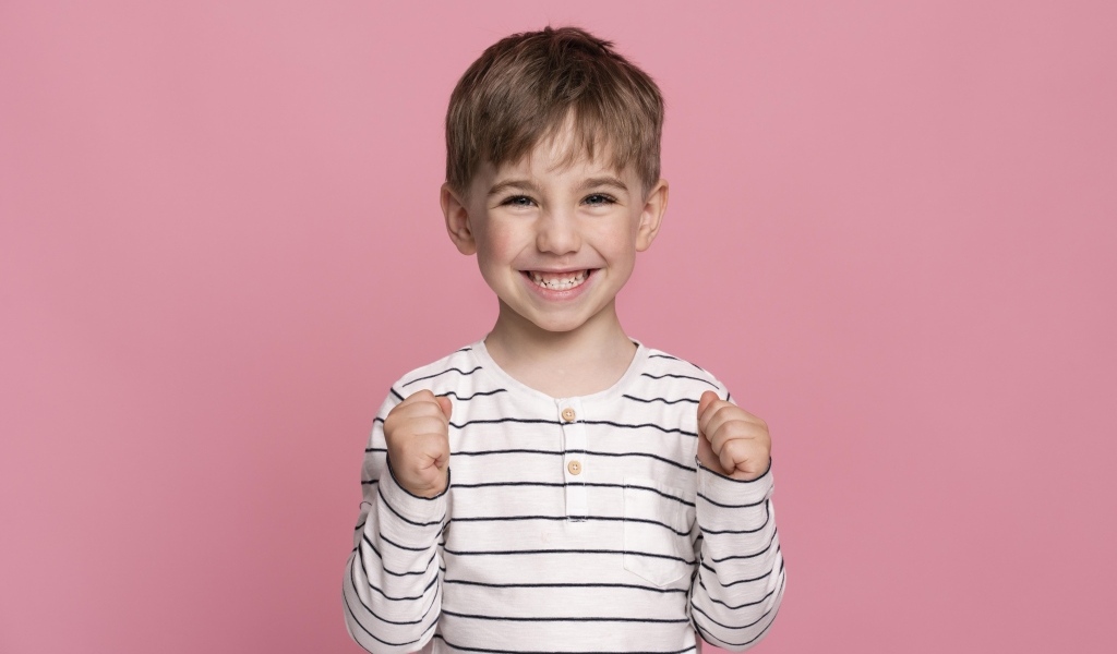 Улыбающийся маленький мальчик на сиреневом фоне