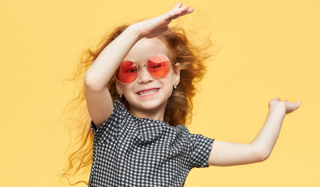 Улыбающаяся рыжеволосая девочка в очках