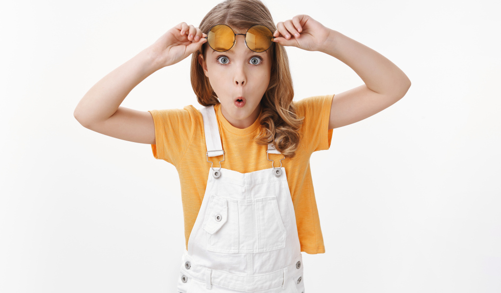 Удивленная девочка в очках на белом фоне