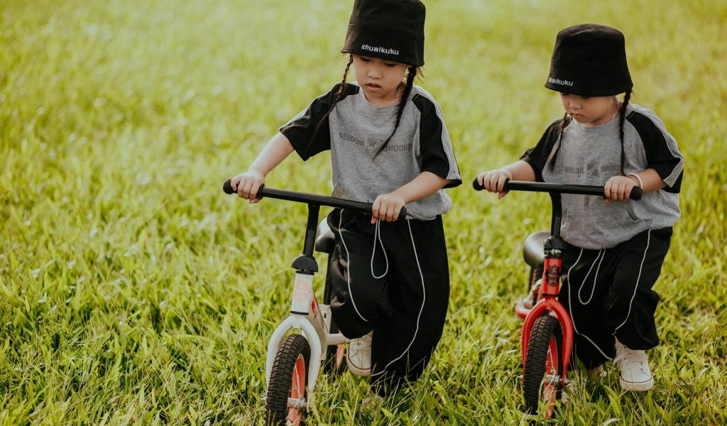 Две девочки с велосипедами на зеленой траве