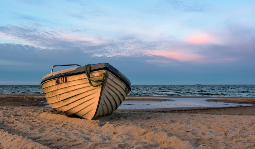 Лодка стоит на песке у моря летом