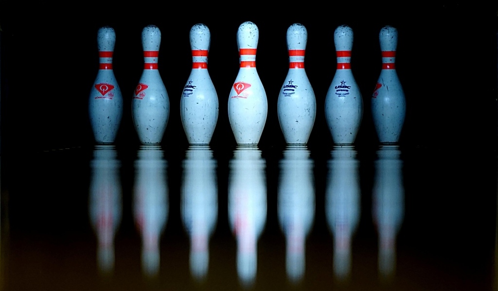 Кегли для боулинга отражаются в черной поверхности 