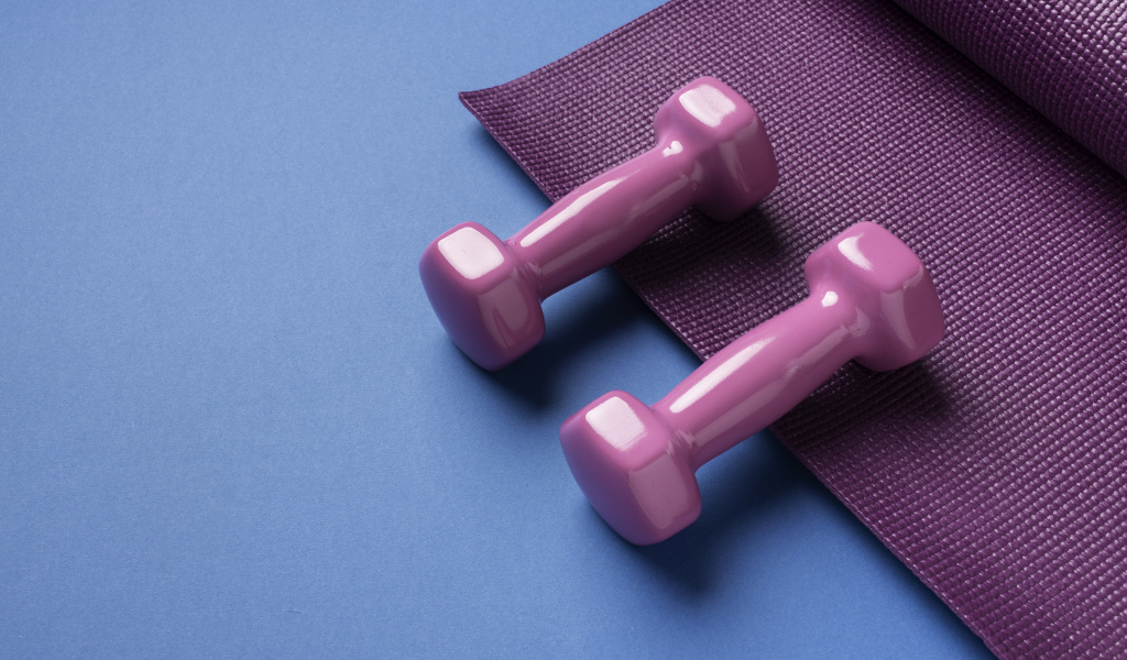 Розовые гантели и коврик на голубом фоне
