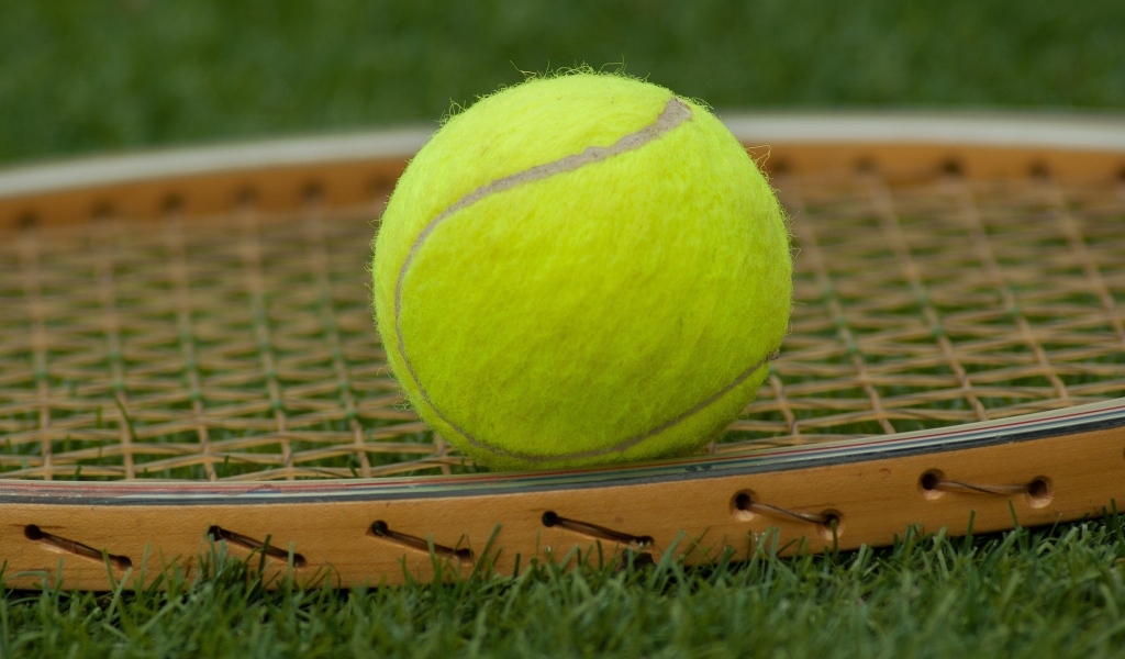 Ракетка и желтый теннисный мяч крупным планом