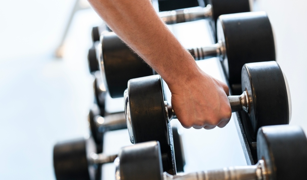 Сильная рука спортсмена берет гантели
