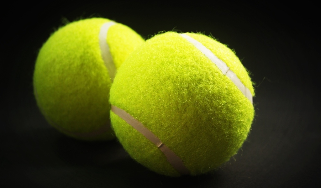 Two yellow tennis balls on a gray background
