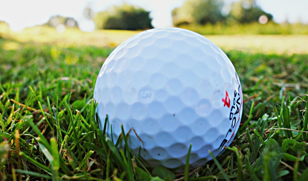 Белый мяч для гольфа в зеленой траве