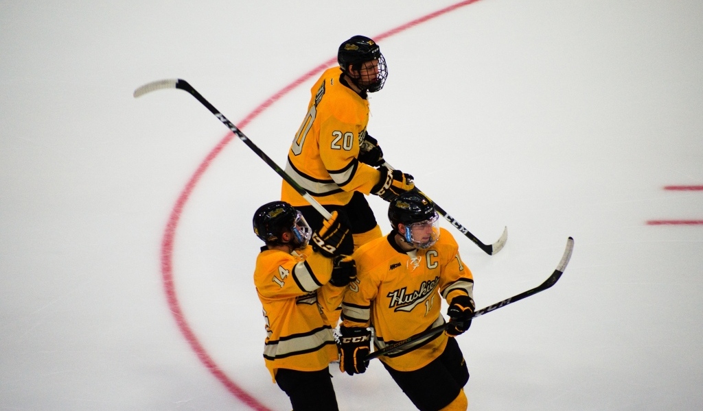 Три хоккеиста с клюшками на льду